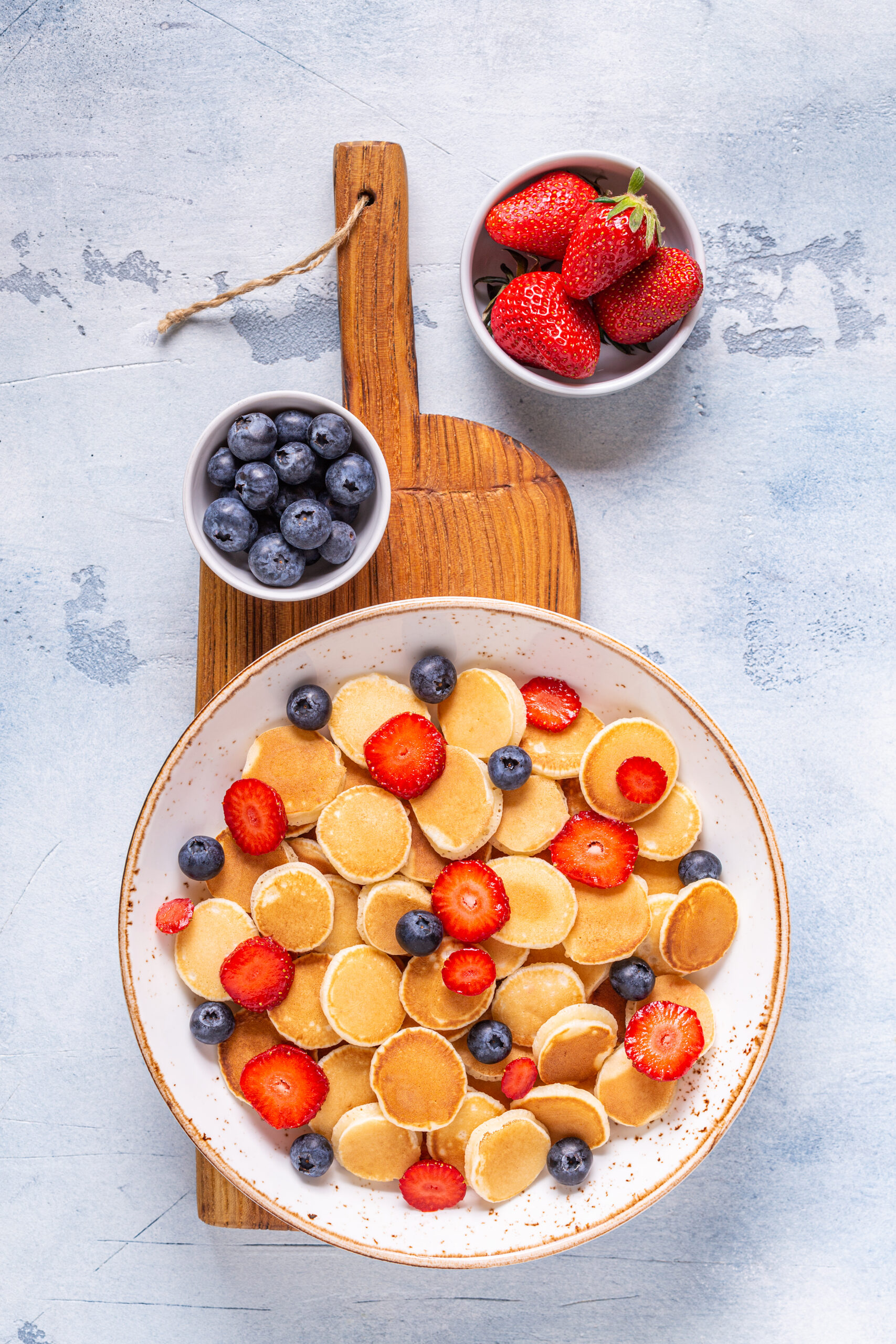 Tiny pancakes with strawberries and blueberries for breakfast.