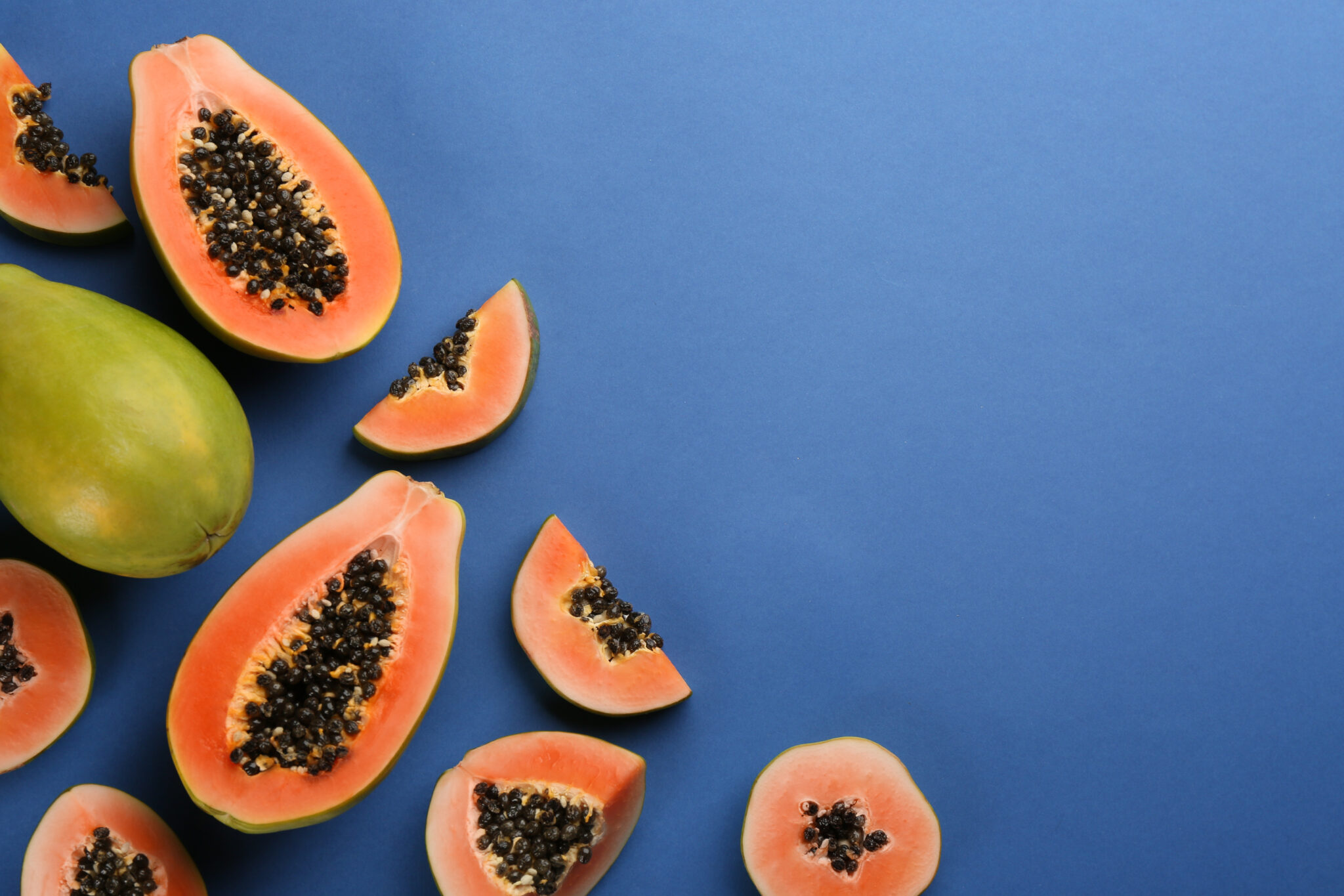 Fresh ripe papaya fruits on blue background, flat lay. Space for