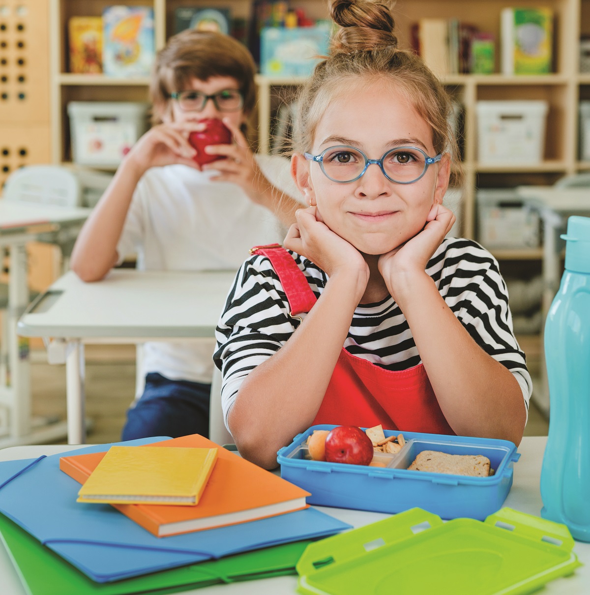 Elementary school students eating from the lunchboxes in the classroom