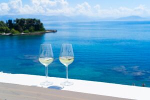 Two glasses of white wine with Corfu in background