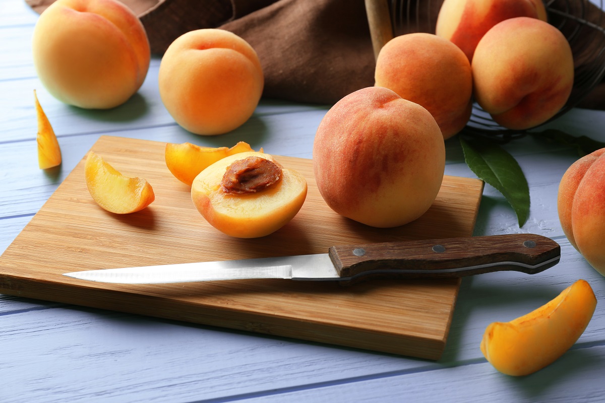 Ripe peaches on cutting board and turquoise wooden background
