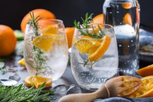 Hard seltzer cocktail with orange, rosemary and bartenders accessories