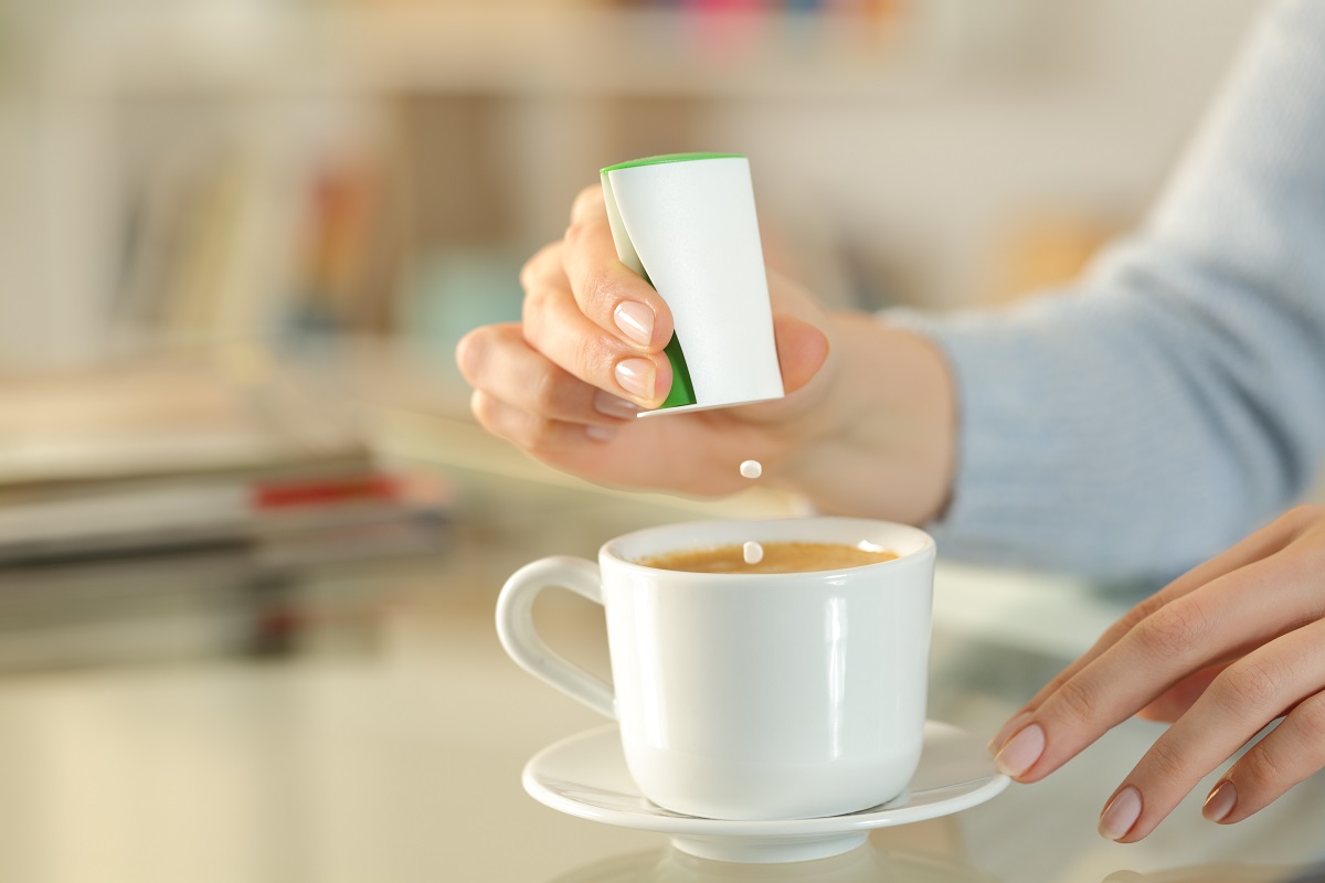 Woman hand throwing saccharin pills on coffee cup