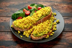 Scrambled Tofu crispy Toast with guacamole and spinach, tomato salad. Vegan vegetarian, plant based food