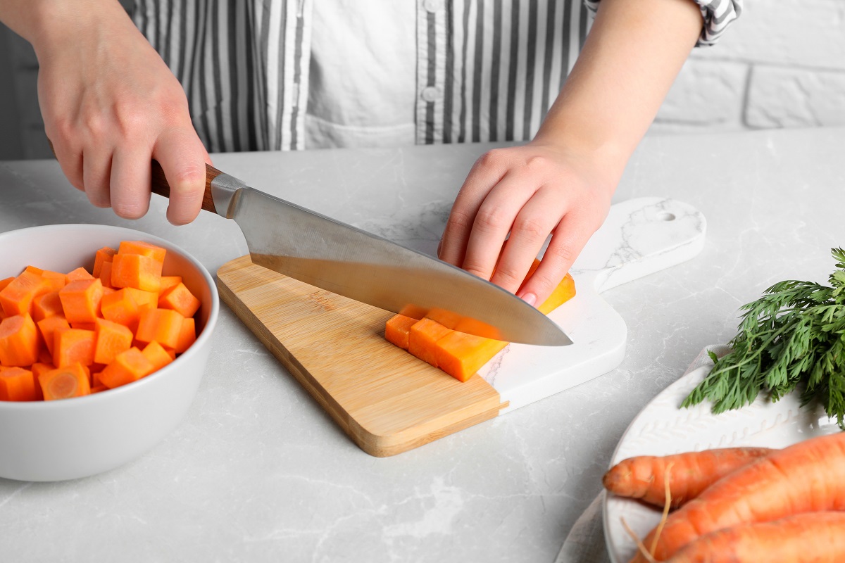 Woman,Cutting,Fresh,Ripe,Juicy,Carrots,At,Light,Grey,Table,