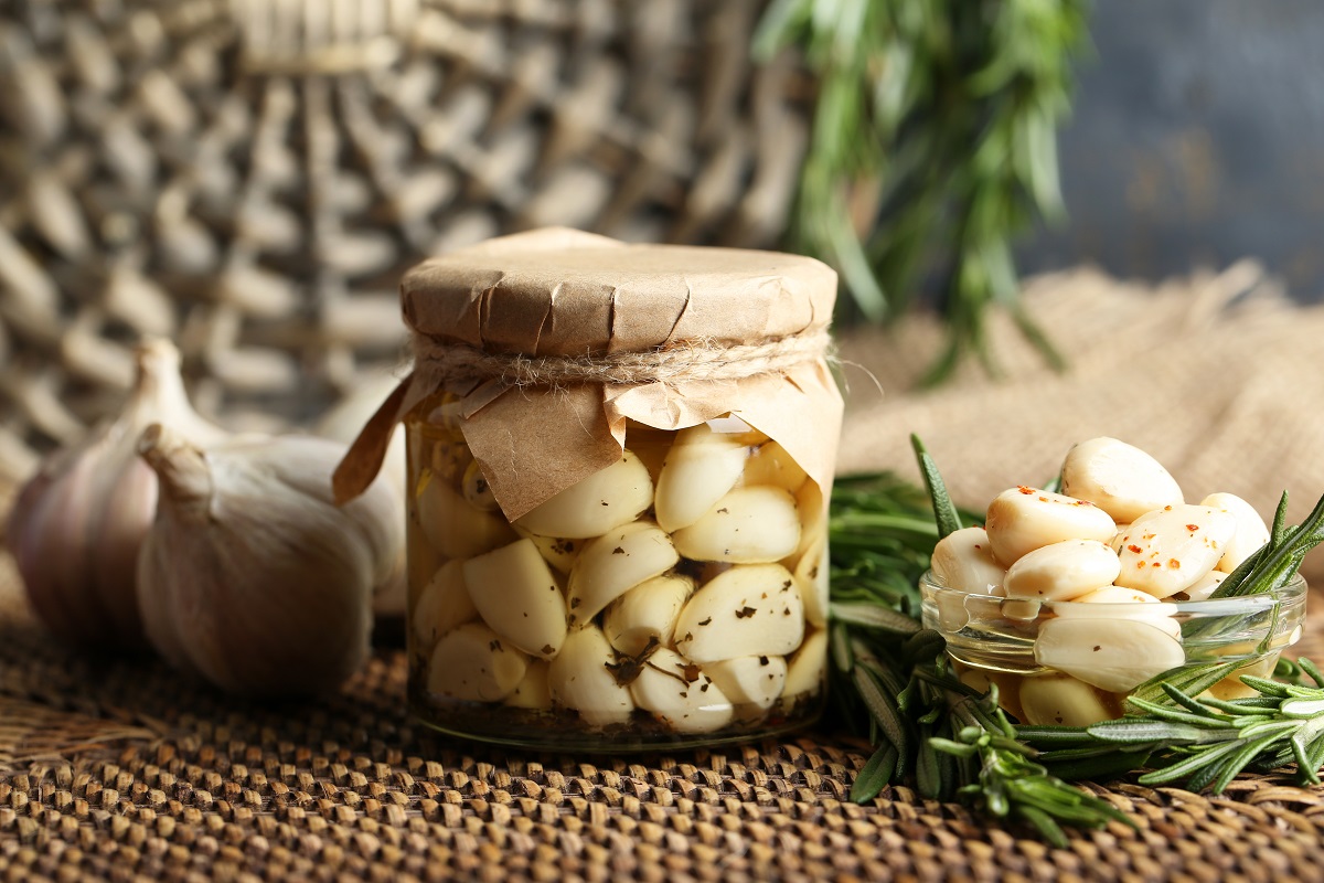 Canned,Garlic,In,Glass,Jar,And,Wicker,Mat,And,Rosemary