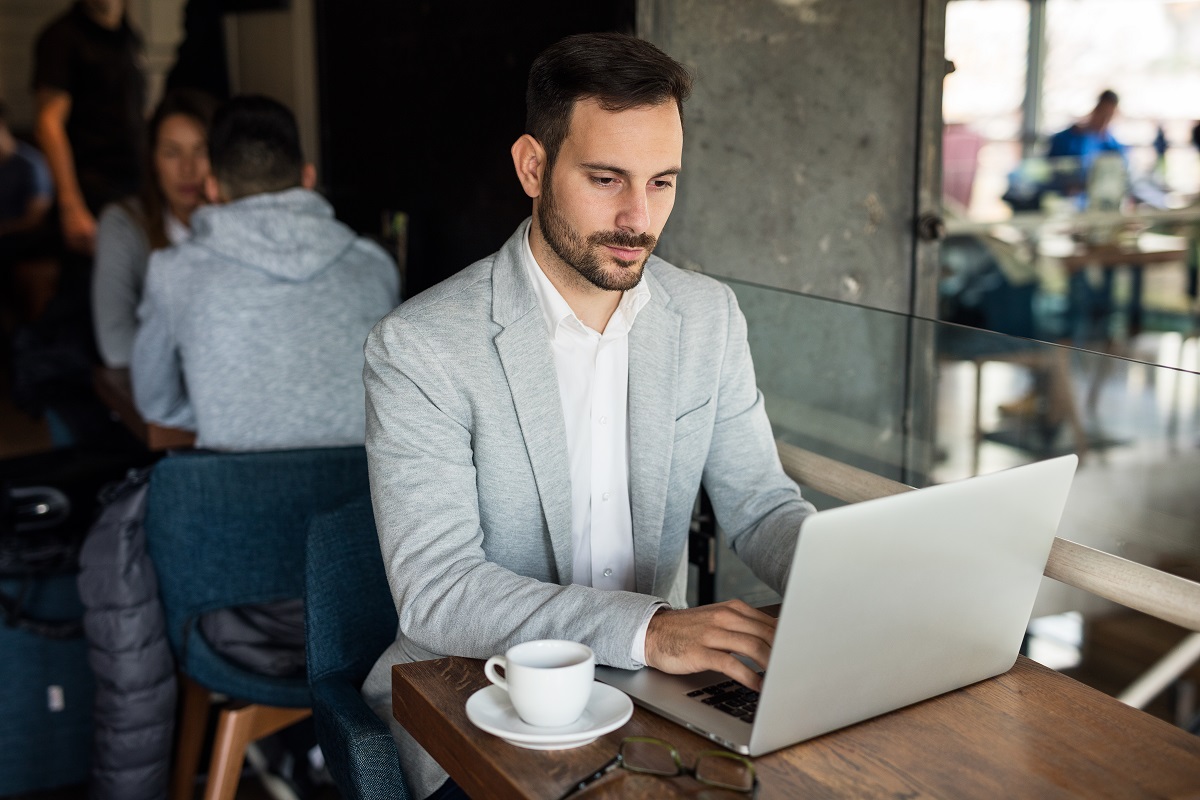 Handsome,Businessman,Using,Laptop,At,City,Cafe.