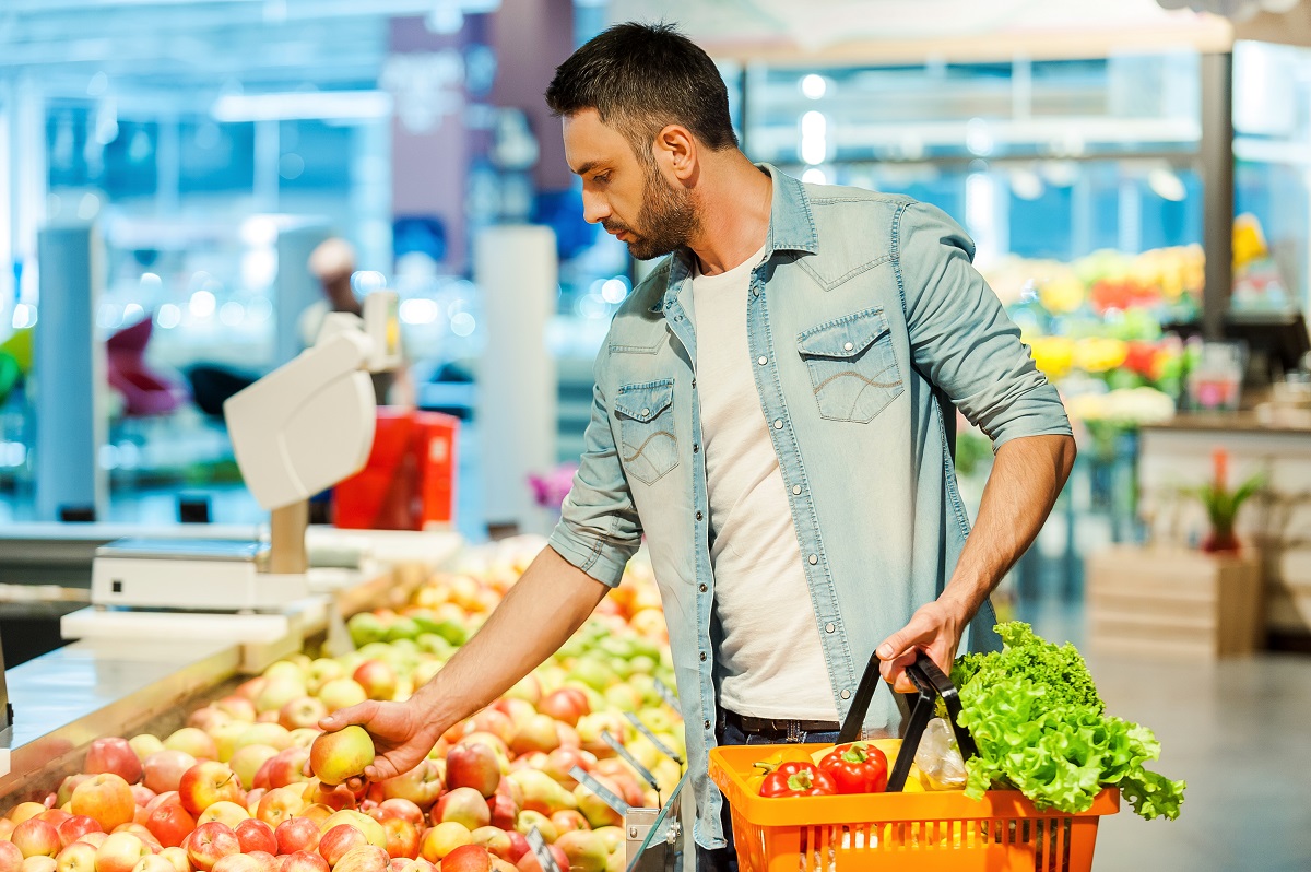 Making,Nutritional,Choice.confident,Young,Man,Holding,Apple,And,Shopping,Bag