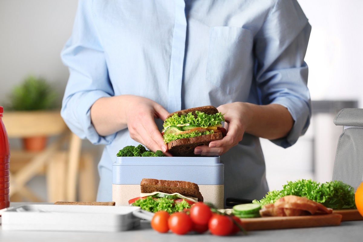 Mother,Packing,Meal,For,School,Lunch,On,Table