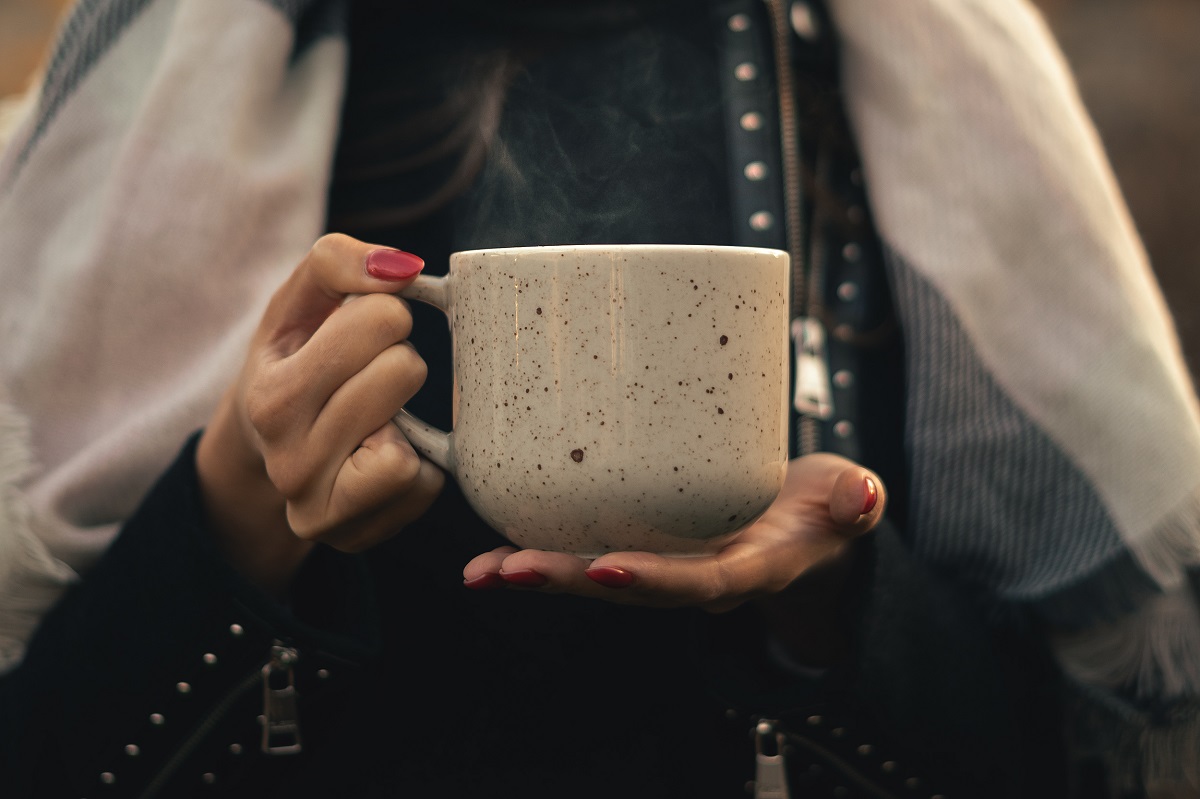 Young,Woman,Holding,A,Cup,Of,Hot,Tea,Outside.,Steam