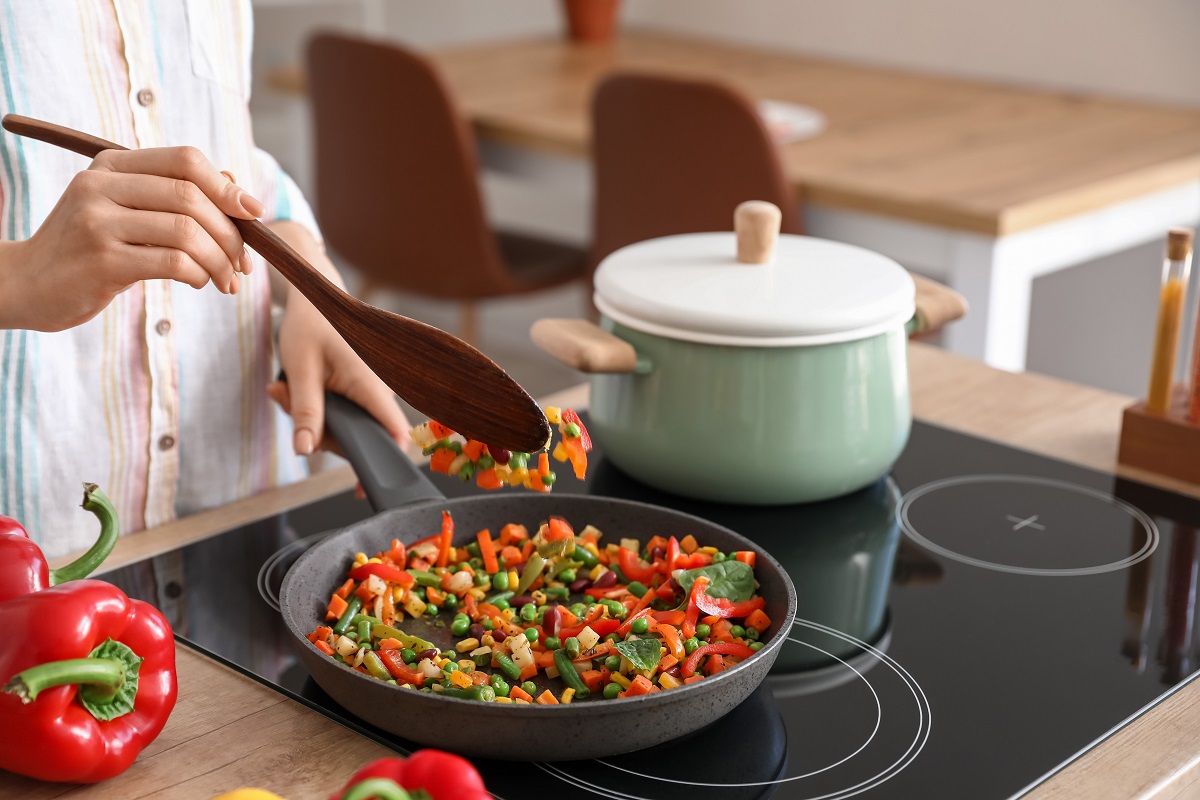 Woman,Frying,Vegetables,In,Kitchen