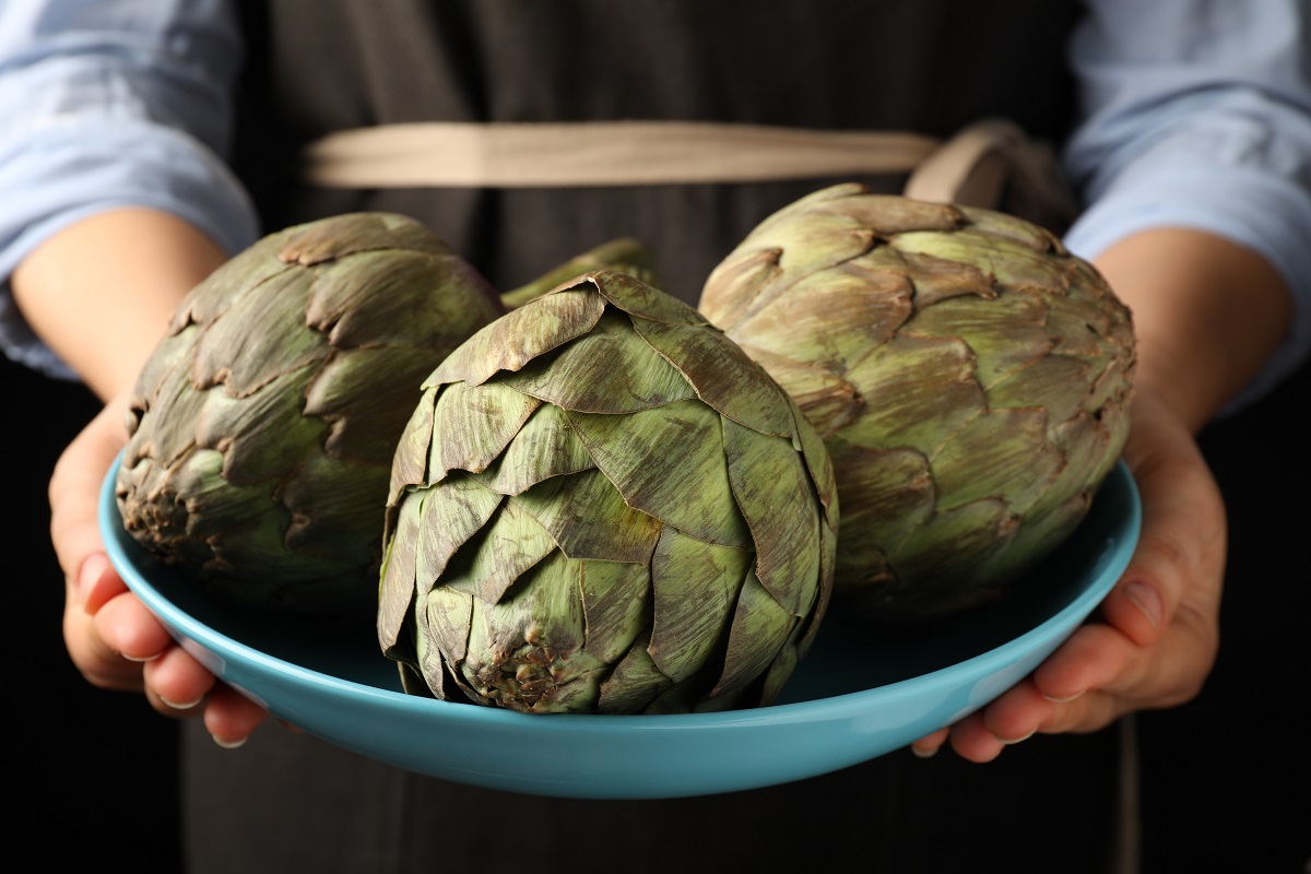 Woman,Holding,Bowl,With,Fresh,Raw,Artichokes,,Closeup