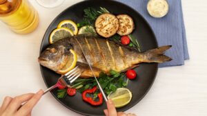 Female,Hands,Cutting,Tasty,Fish,On,Plate