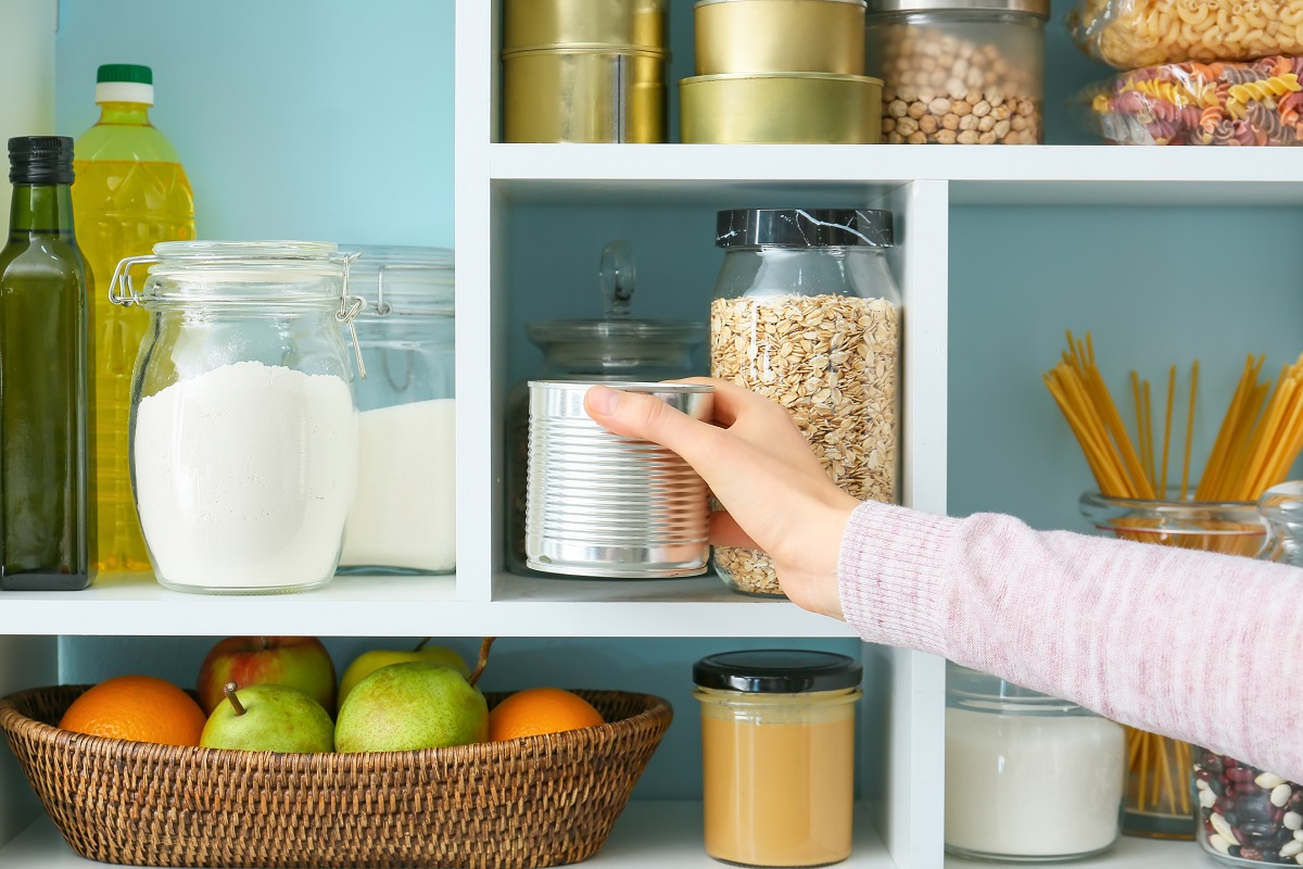 Woman,Taking,Metal,Can,From,Shelves,With,Products,In,Kitchen