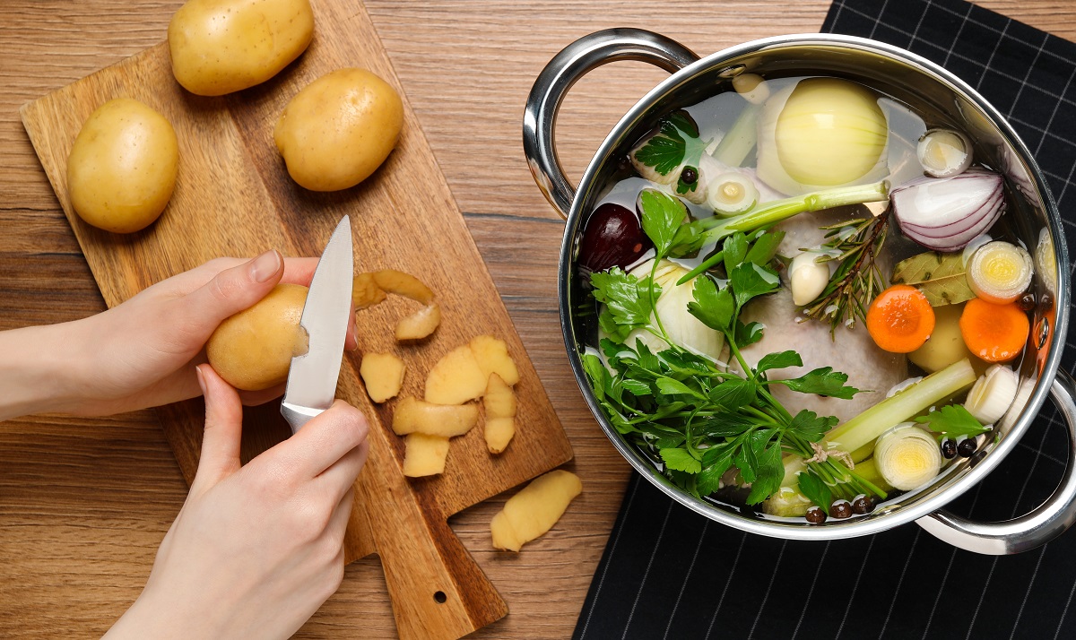 Woman,Peeling,Potato,For,Cooking,Tasty,Bouillon,At,Wooden,Table,