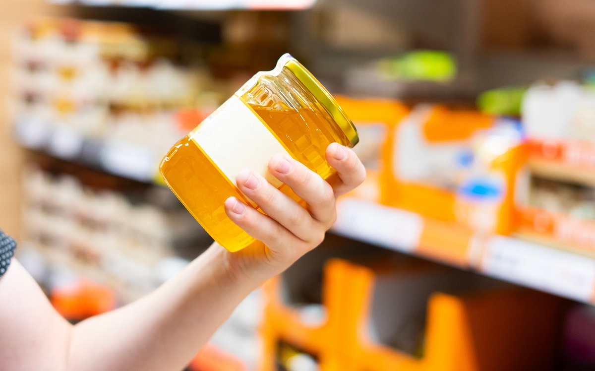 Young,Male,Hand,Holds,Honey,On,A,Blurred,Background,,A