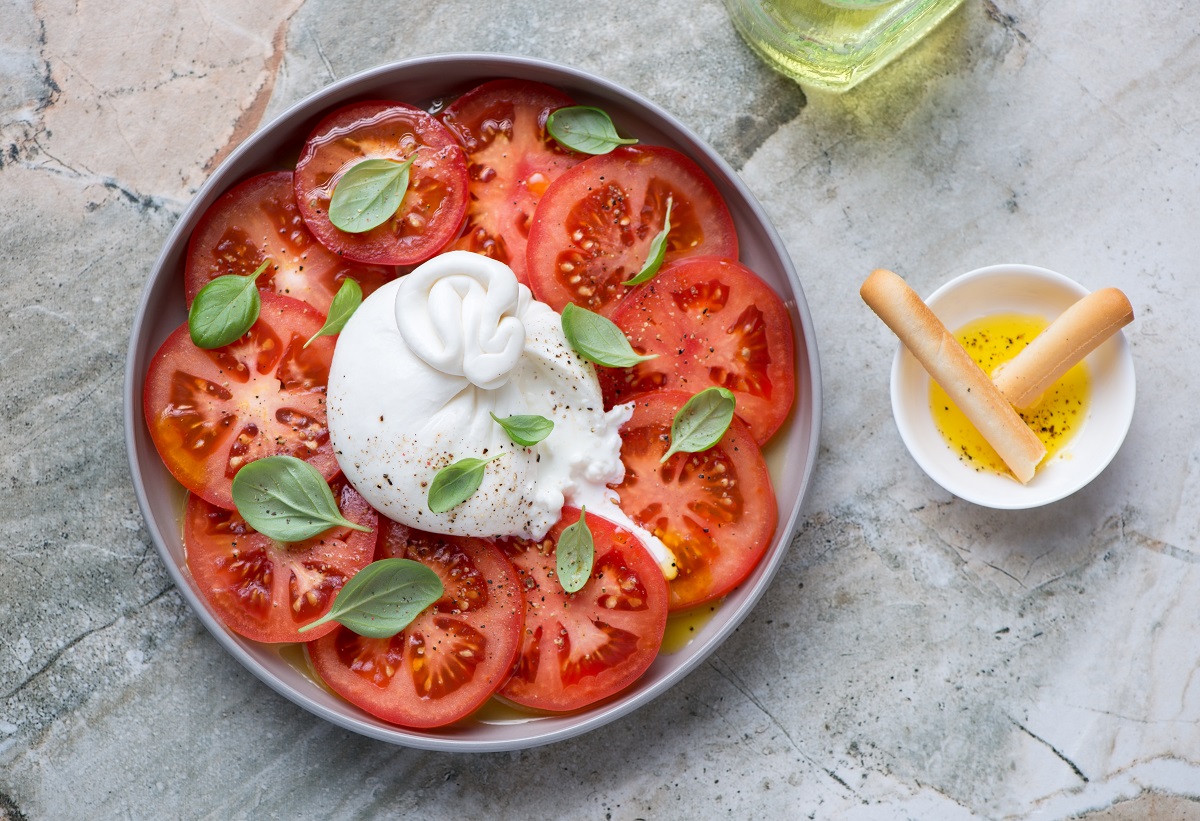 Burrata,Cheese,Served,With,Red,Tomatoes,And,Green,Basil,Leaves,