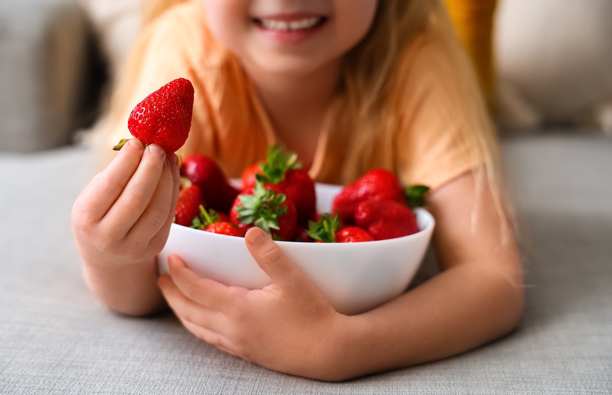 Little,Girl,Eating,Delicious,Strawberries,In,Living,Room