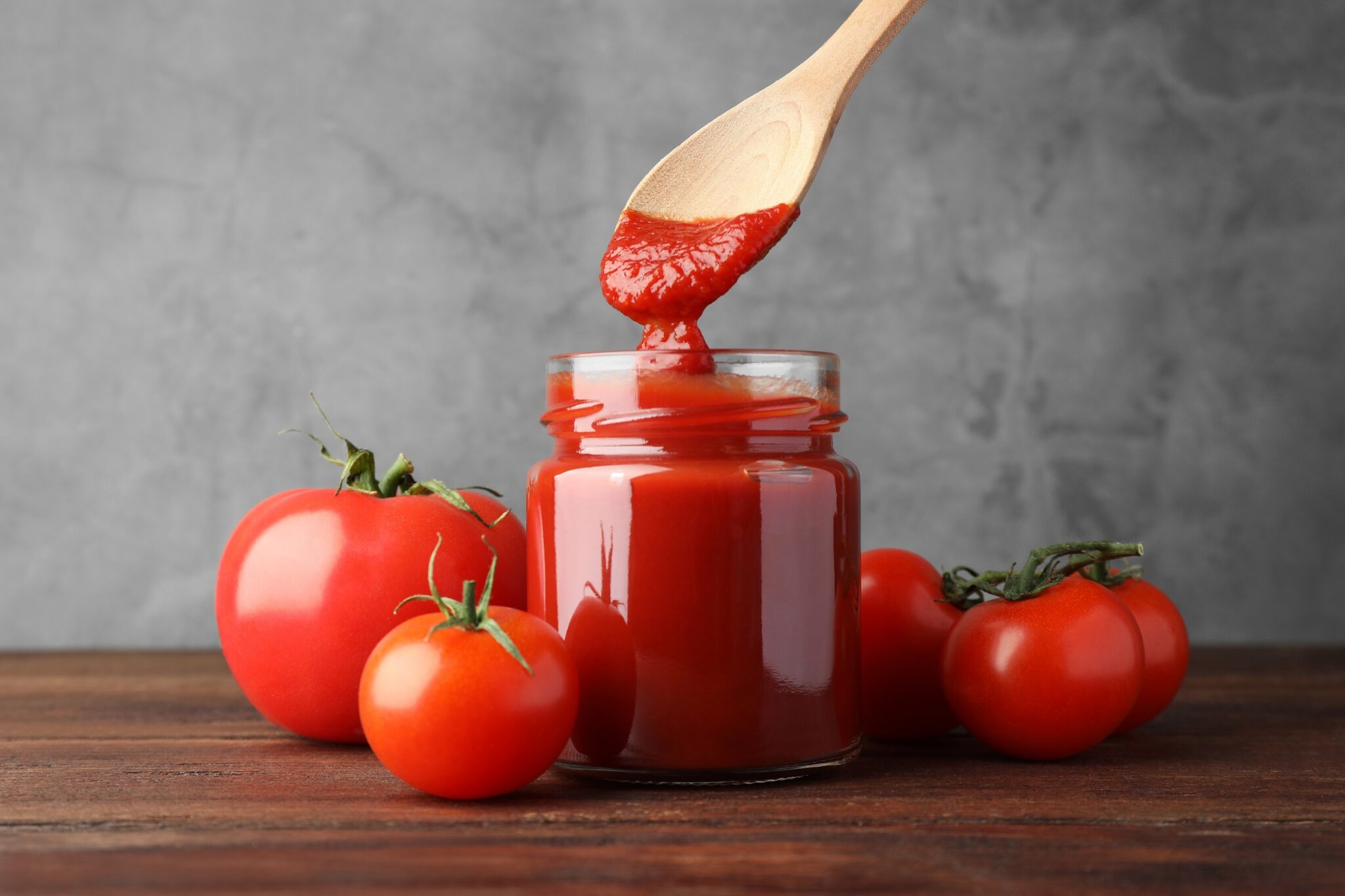 Taking,Tasty,Ketchup,With,Spoon,From,Jar,On,Wooden,Table,