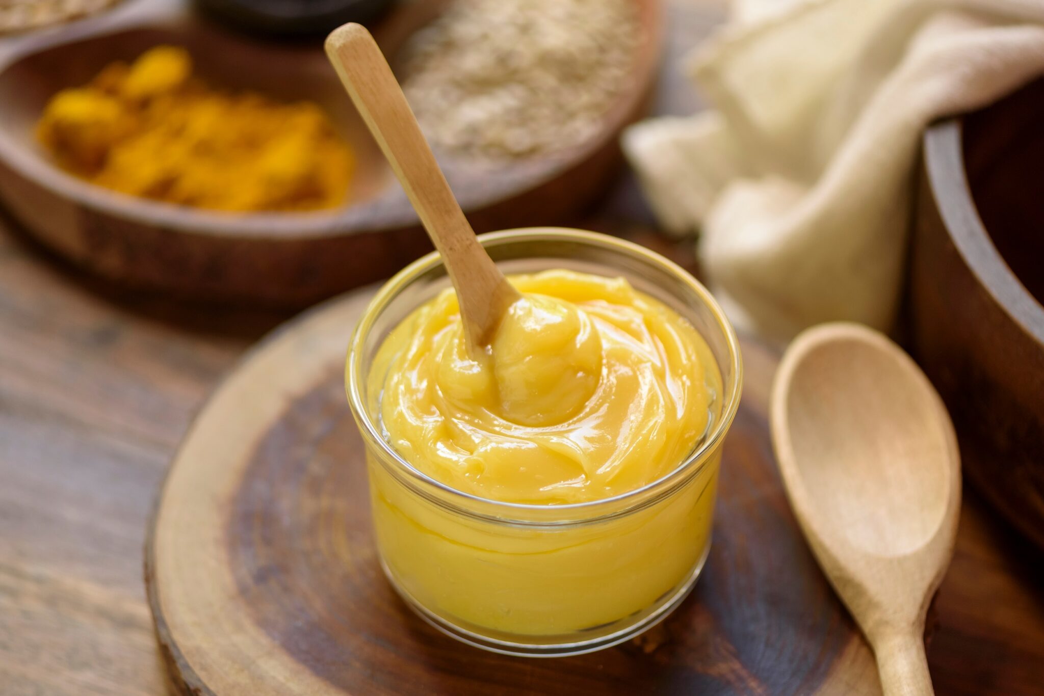 Ghee,Butter,In,Glass,Jar,With,Wooden,Spoon,On,Wooden