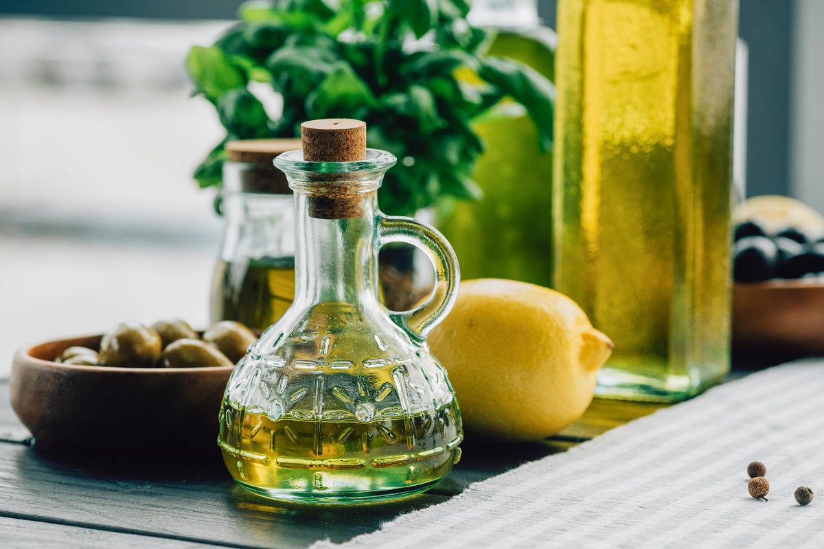 Olive,Oil,Bottles,With,Vegetables,On,Wooden,Table
