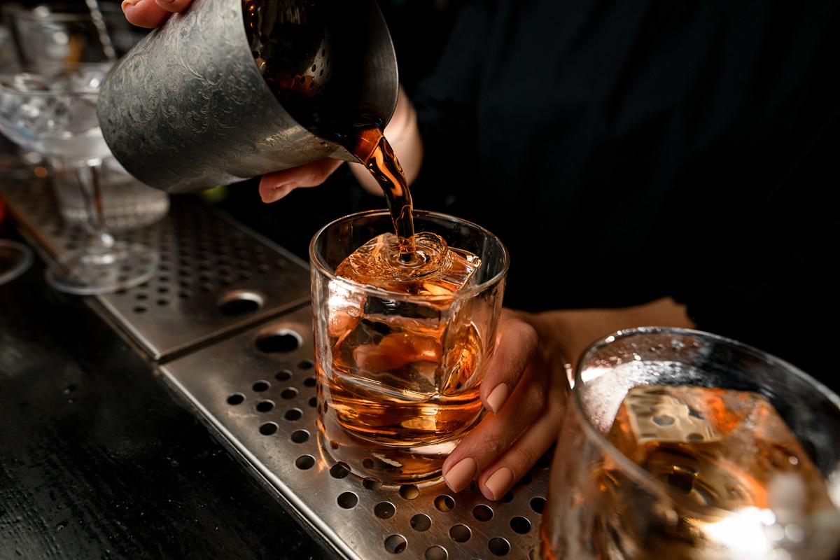 Close-up.,Bartender’s,Hand,Gently,Pours,Cocktail,Into,Glass,With,Large