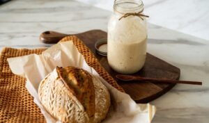 Crispy,Sourdough,Bread,Sits,Beside,A,Glass,Jar,Filled,With