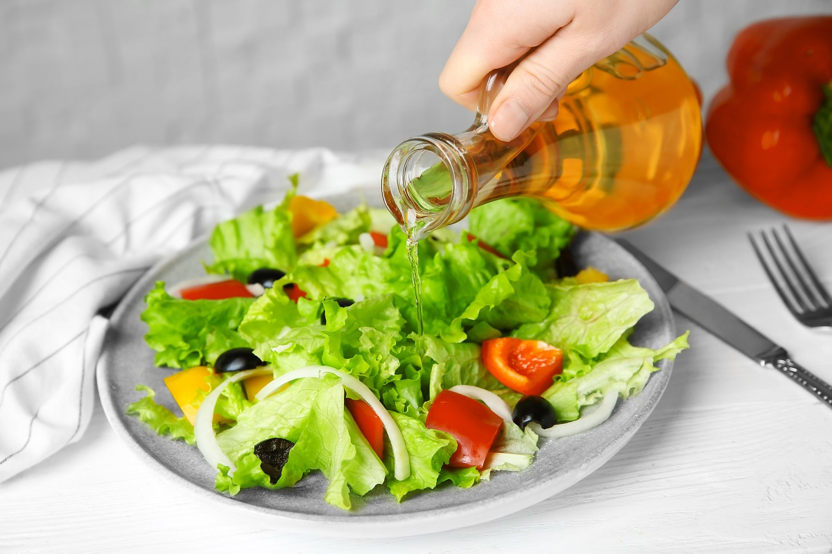 Woman,Adding,Tasty,Apple,Vinegar,Into,Salad,With,Vegetables,On