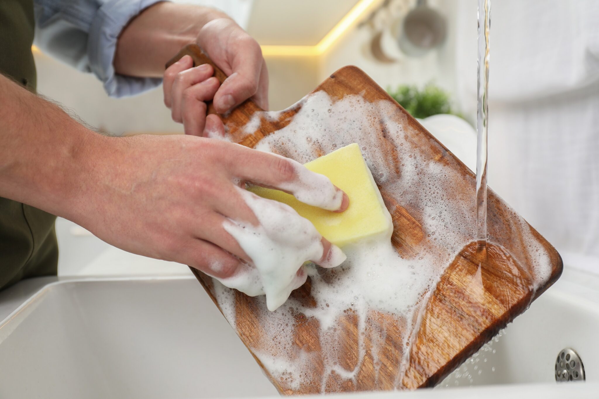 Man,Washing,Wooden,Cutting,Board,In,Kitchen,,Closeup