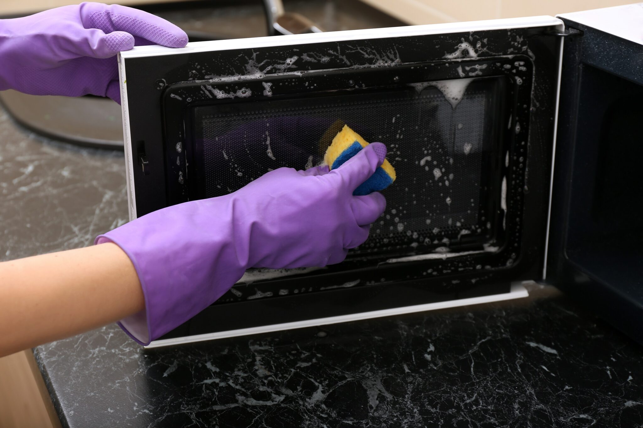 Young,Woman,Cleaning,Microwave,Oven,In,Kitchen