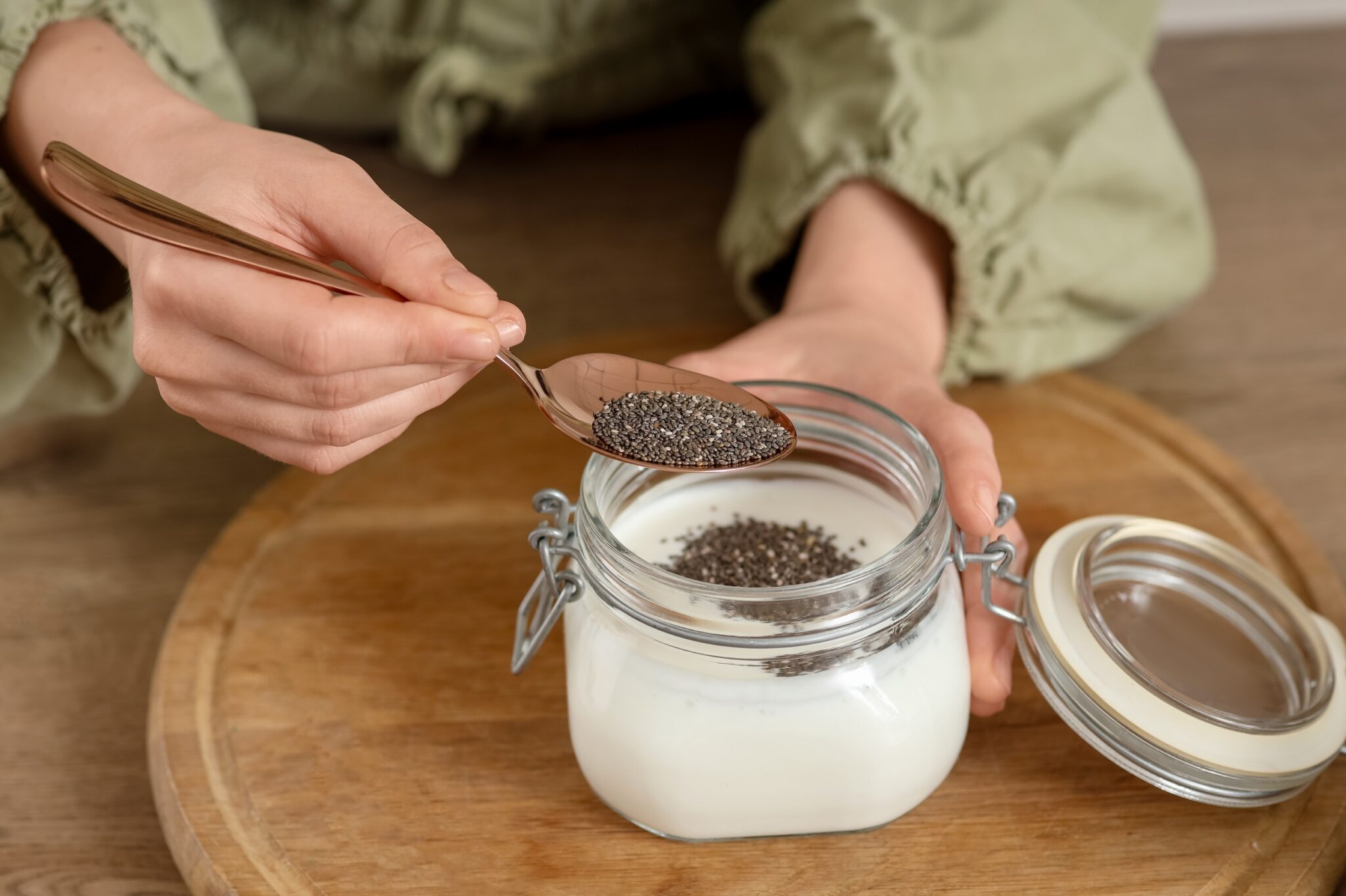 Young,Woman,Making,Chia,Seed,Pudding,At,Table,In,Kitchen,