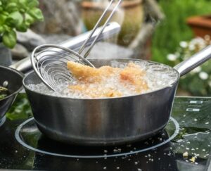 Slotted,Spoon,Takes,Golden,Deep-fried,Chicken,Pieces,From,A,Steaming