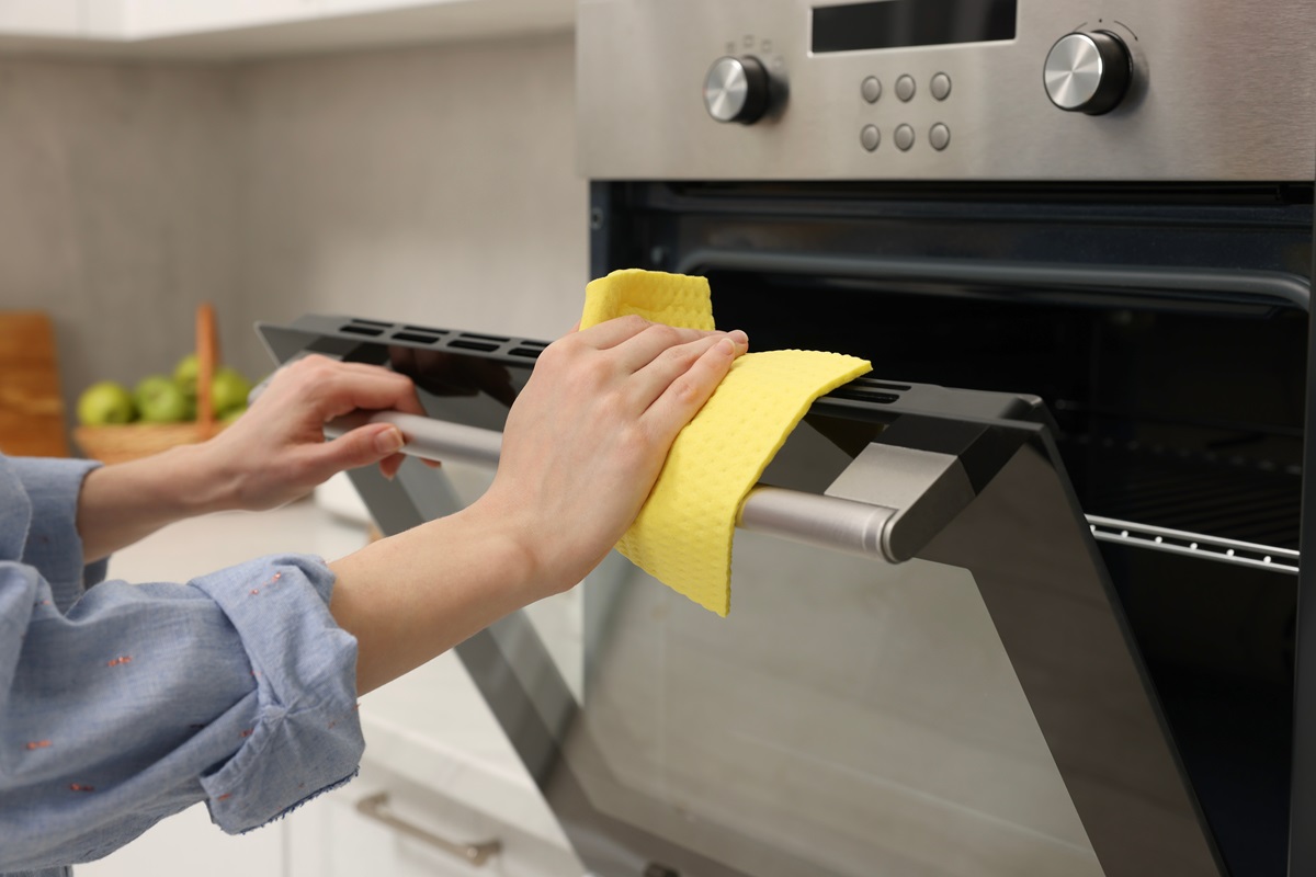 Woman,Cleaning,Electric,Oven,With,Rag,In,Kitchen,,Closeup