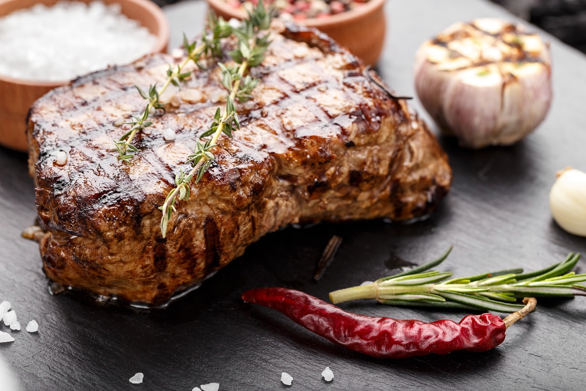 Grilled,Beef,Steak,With,Spices,On,A,Black,Slate,Board.