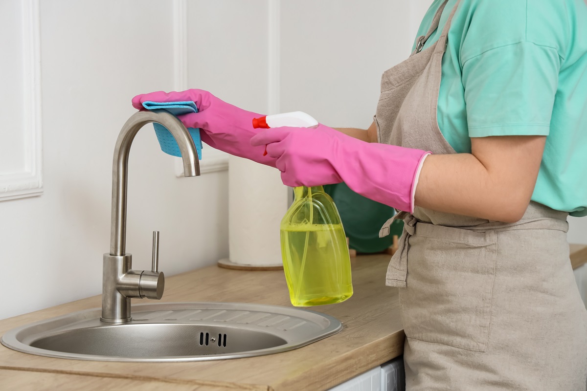 Young,Woman,Cleaning,Faucet,In,Kitchen,,Closeup