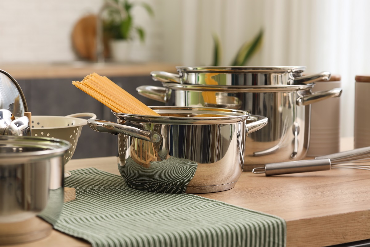 Stainless,Cooking,Pots,With,Pasta,And,Utensils,On,Wooden,Table