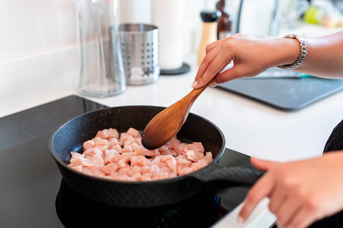 Woman’s,Hands,Stirring,Raw,Chicken,Pieces,In,A,Black,Frying